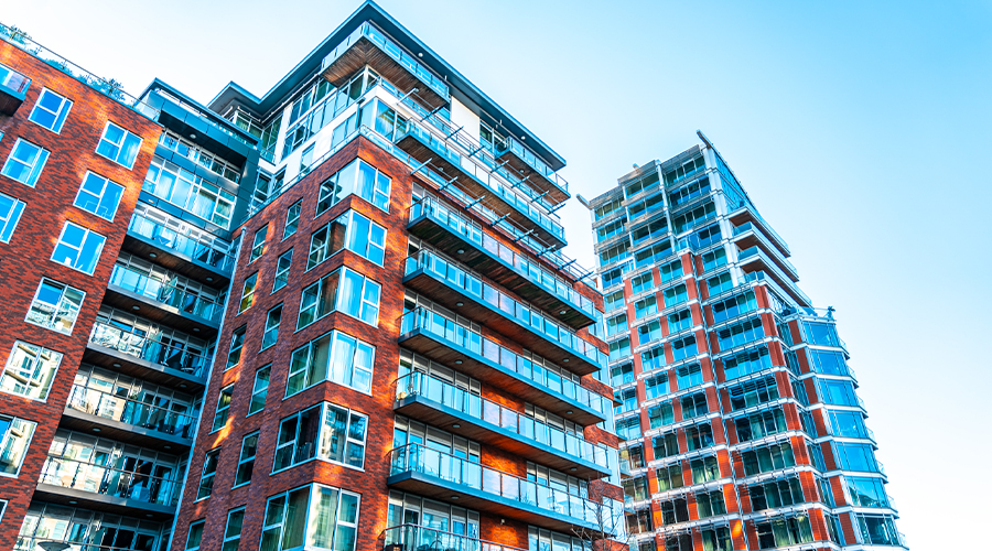 Modern high-rise apartment buildings with red-brick façades, glass balconies and large windows.
