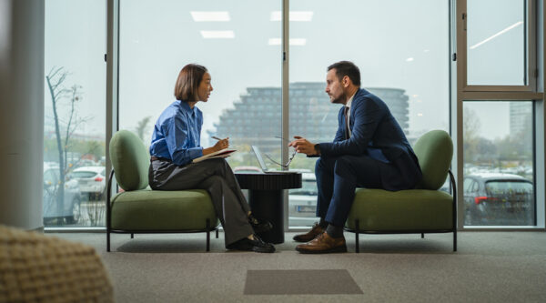 Two professionals discussing business matters across a table in a modern office.