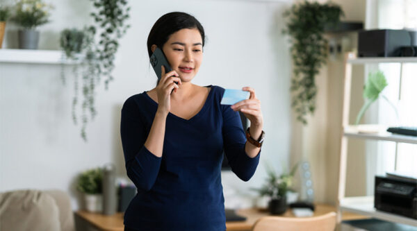 Person speaking on a smartphone while holding a payment card, illustrating a Buy Now, Pay Later purchase.