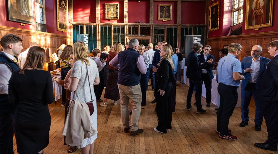 Guests networking at a Future Workspaces event in a historic wood-panelled hall with framed portraits.